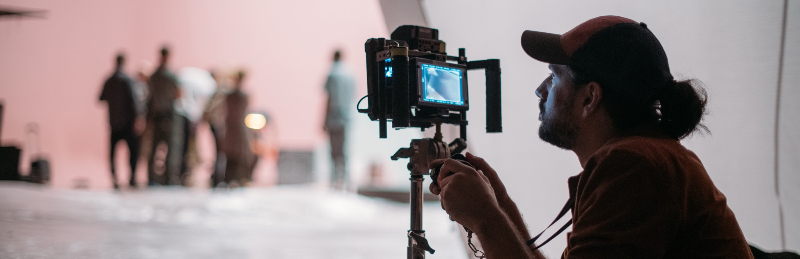 A focus puller checks a monitor while the crew lights a set